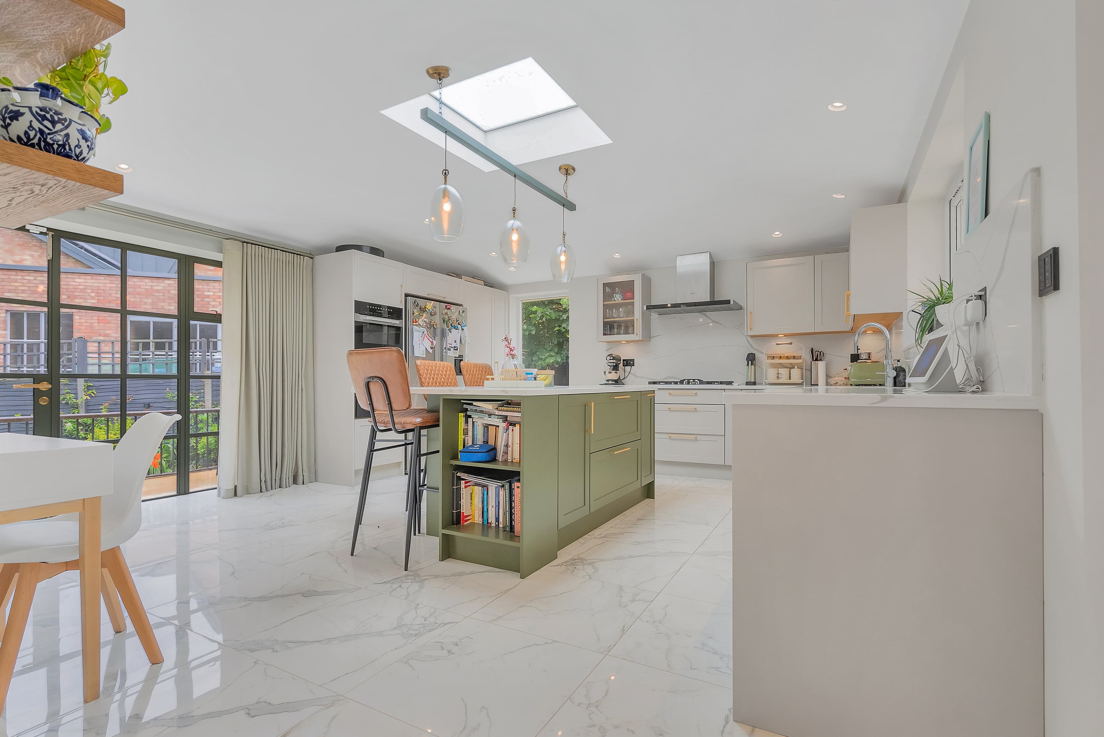Kitchen with sage green island and marble-effect flooring