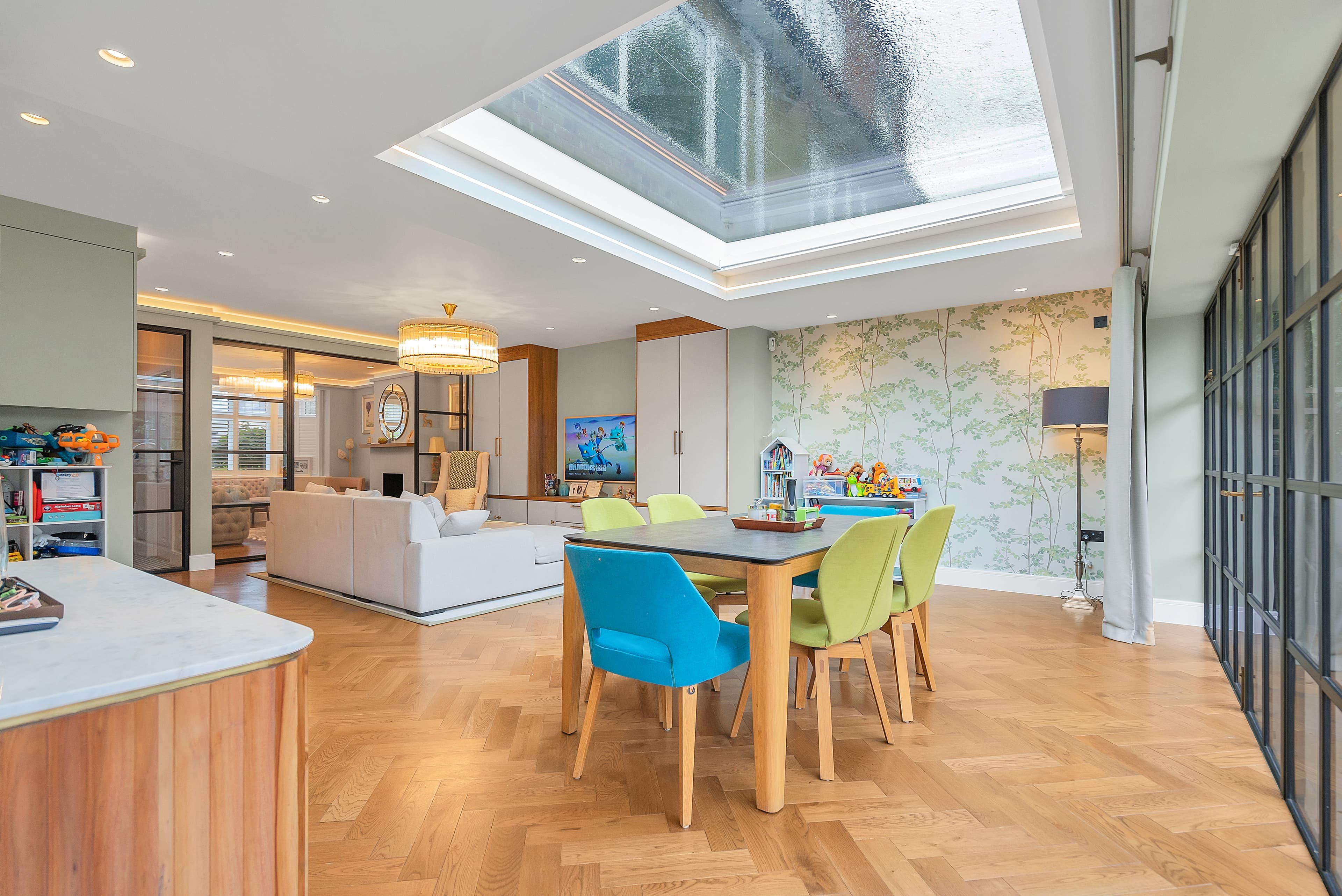 Open-plan family living with gold chandelier and skylight