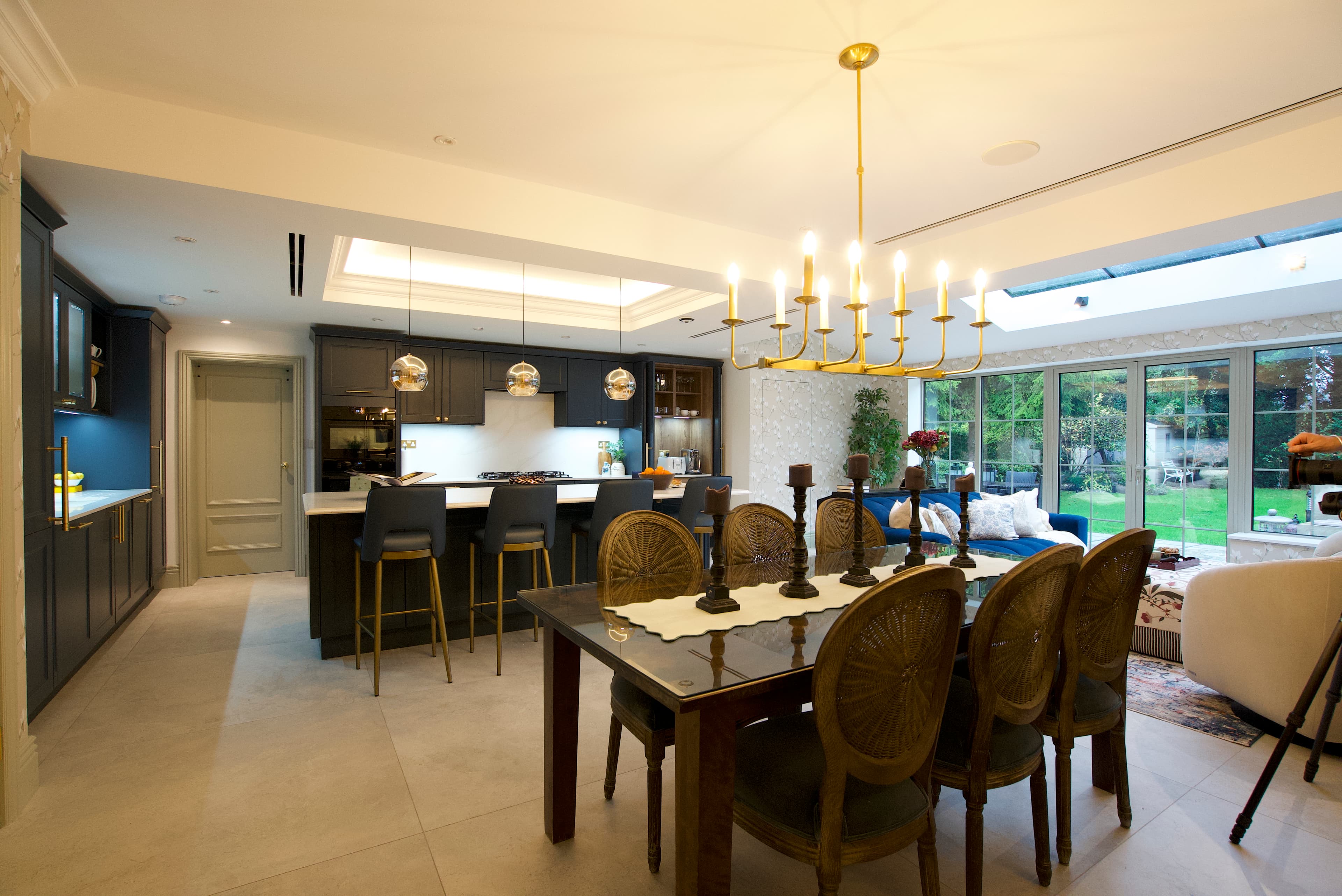 Open-plan kitchen with navy cabinetry and brass chandelier