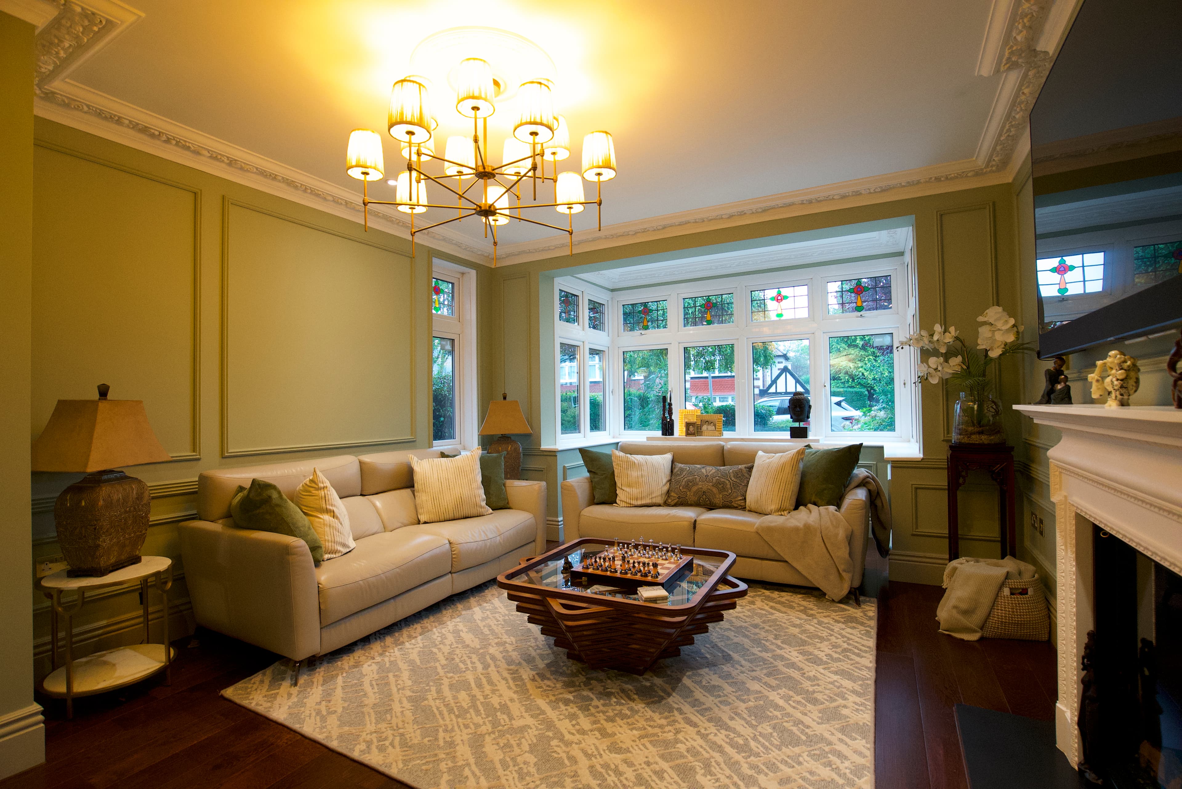 Formal living room with sage panelling and brass chandelier