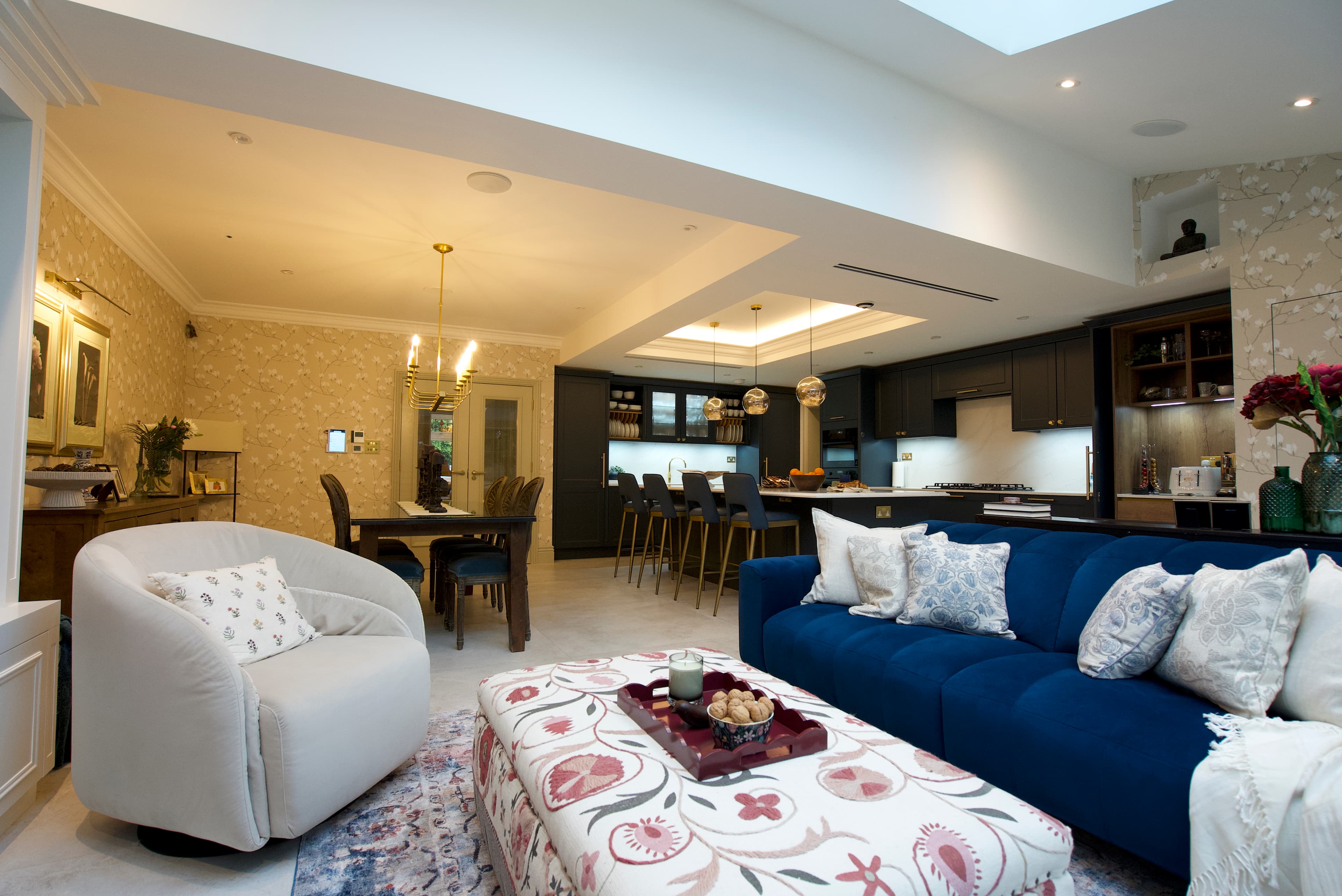 Living area with navy velvet seating and botanical wallpaper