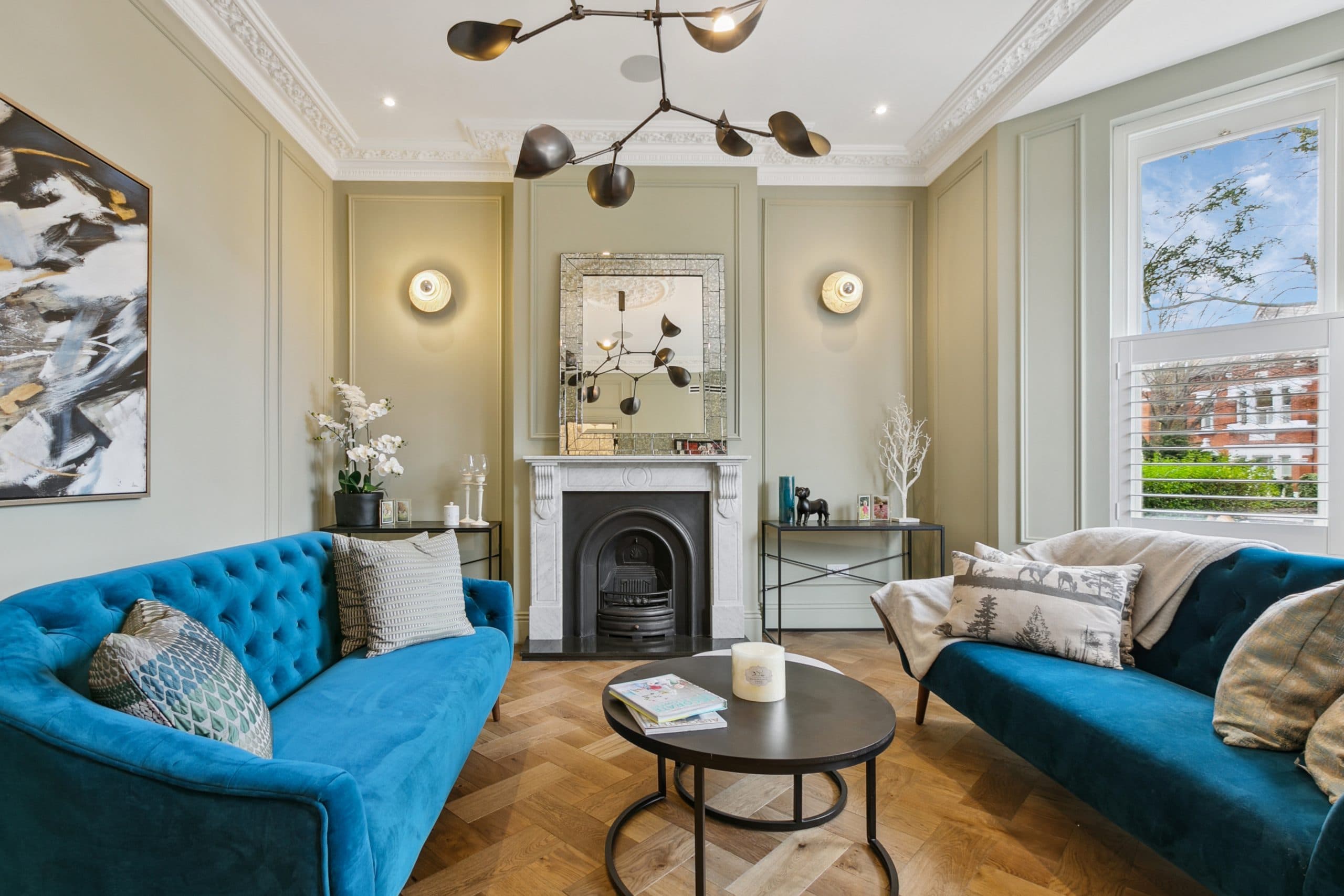 Formal living room with teal sofas and period fireplace