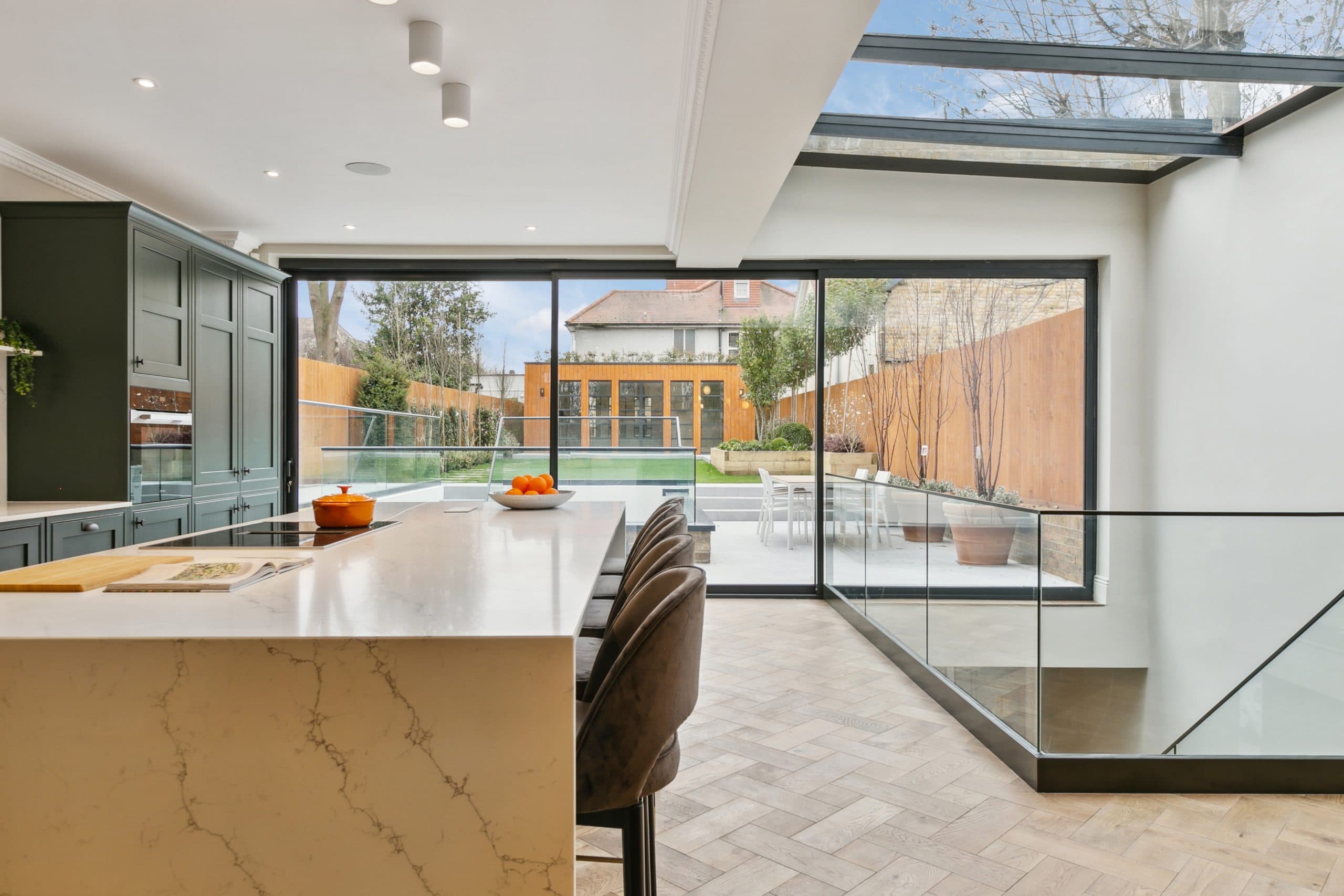 Kitchen opening to terrace with glass balustrade