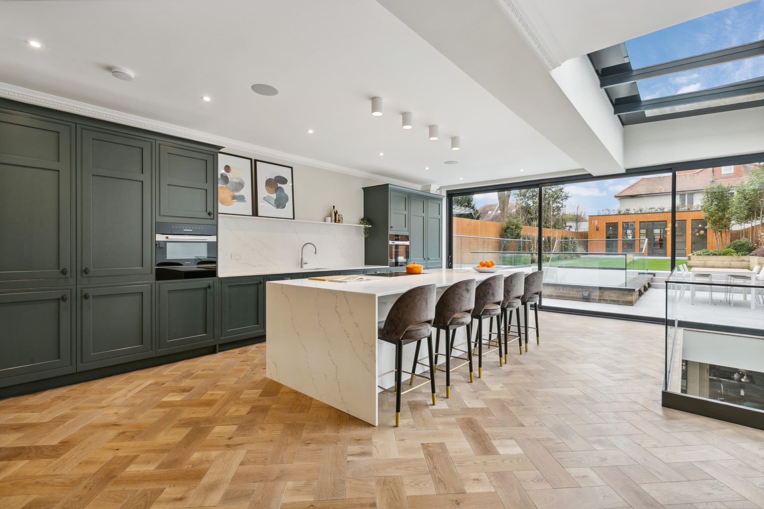 Open-plan kitchen with sage-green shaker cabinetry and quartz island